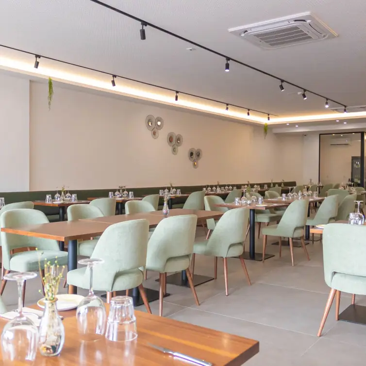 Sala do restaurante Sem Rumo com mesas em madeira e cadeiras verdes